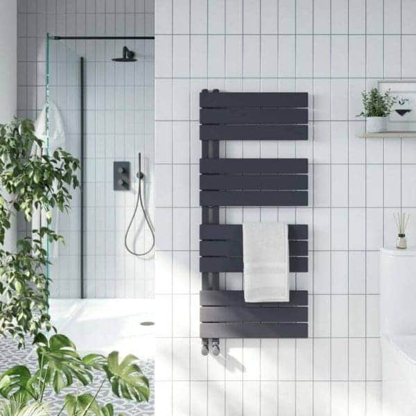 Modern white tiled bathroom with black wooden towel radiator and walk-in shower area, featuring green plants and minimalistic decor, perfect for contemporary bathroom design and renovation.