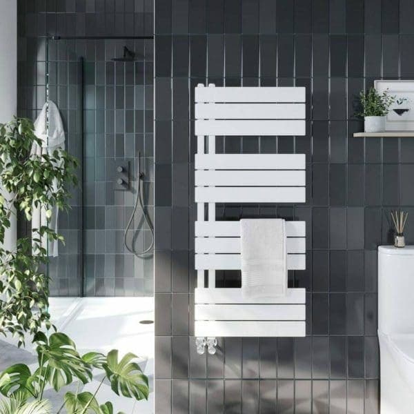 Modern black-tiled bathroom with white heated towel rail, shower area, and green houseplants, creating a stylish and relaxing space.
