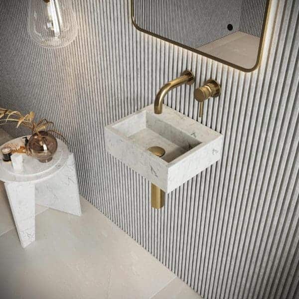 Elegant white marble bathroom sink with gold fixtures, modern wall mirror, and stylish decor in a contemporary bathroom setting.
