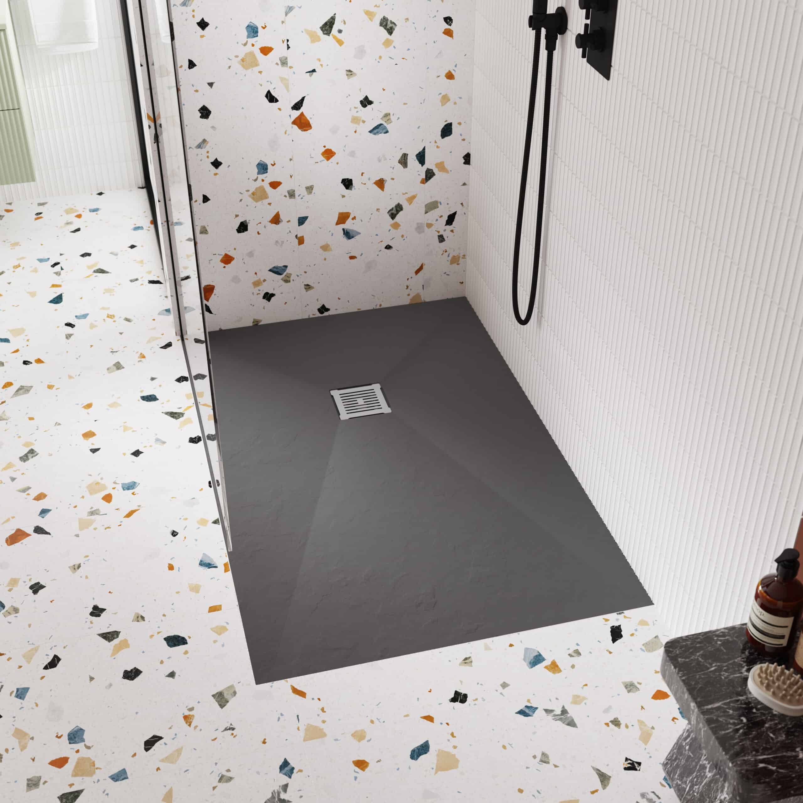Sleek walk-in shower with terrazzo and grey flooring, modern white tiles, black fixtures, and a stylish soap dispenser, creating a contemporary bathroom design.