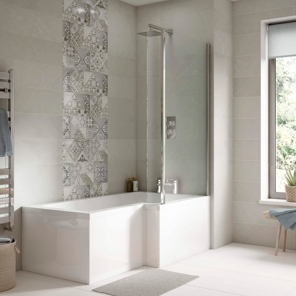 Modern bathroom with a white bathtub, glass shower screen, neutral tiles with decorative pattern, and natural light from a large window, showcasing luxurious Bubly Bathrooms design.