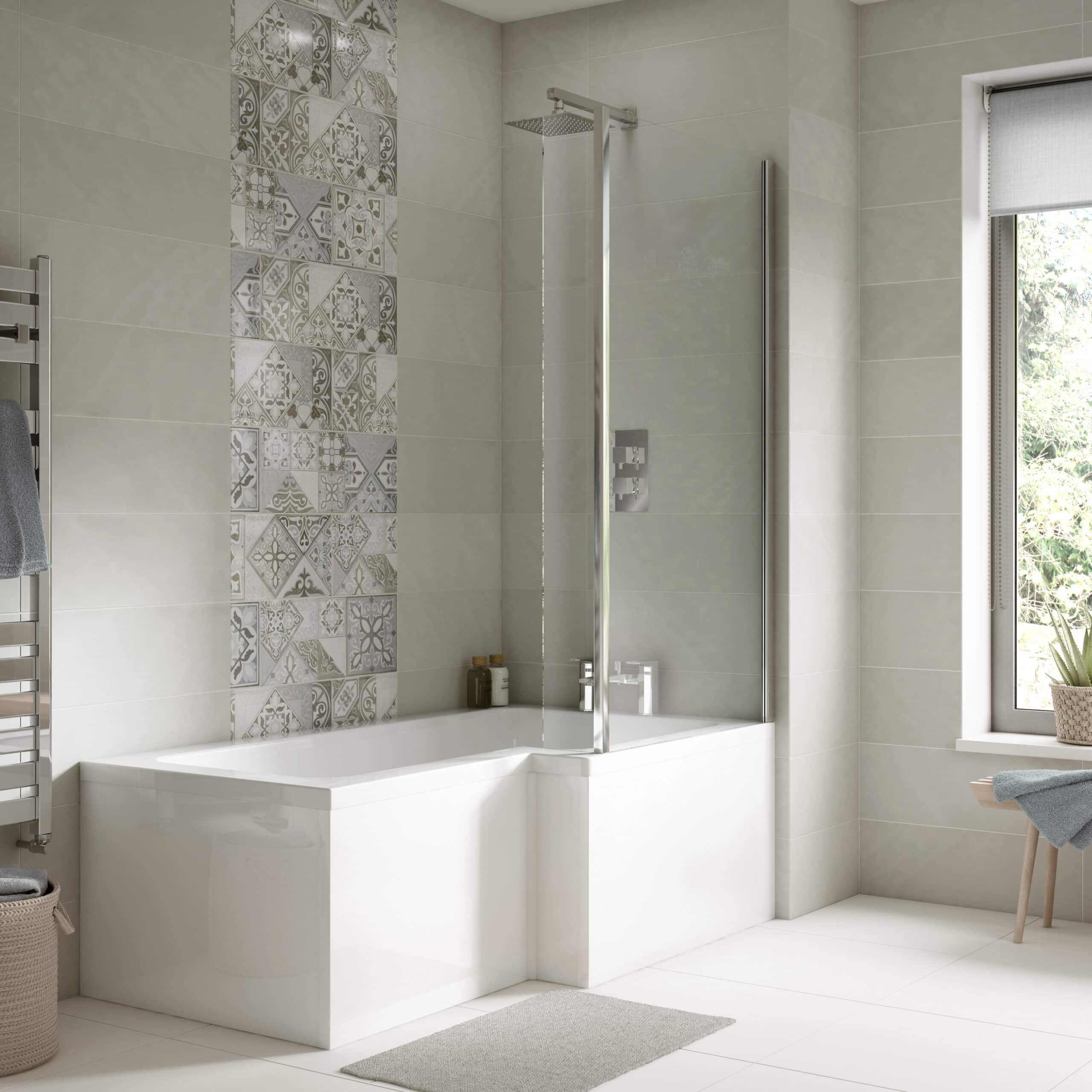 Modern bathroom with a white bathtub, glass shower screen, neutral tiles with decorative pattern, and natural light from a large window, showcasing luxurious Bubly Bathrooms design.