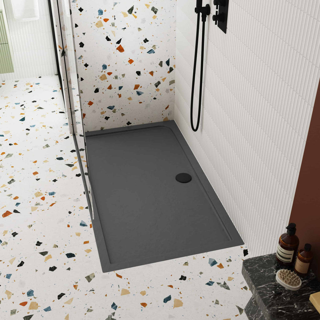 Modern grey shower tray with corner installation, terracotta terrazzo bathroom flooring, contemporary black shower fixtures, and stylish white wall tiles, creating a chic and functional bathroom space.