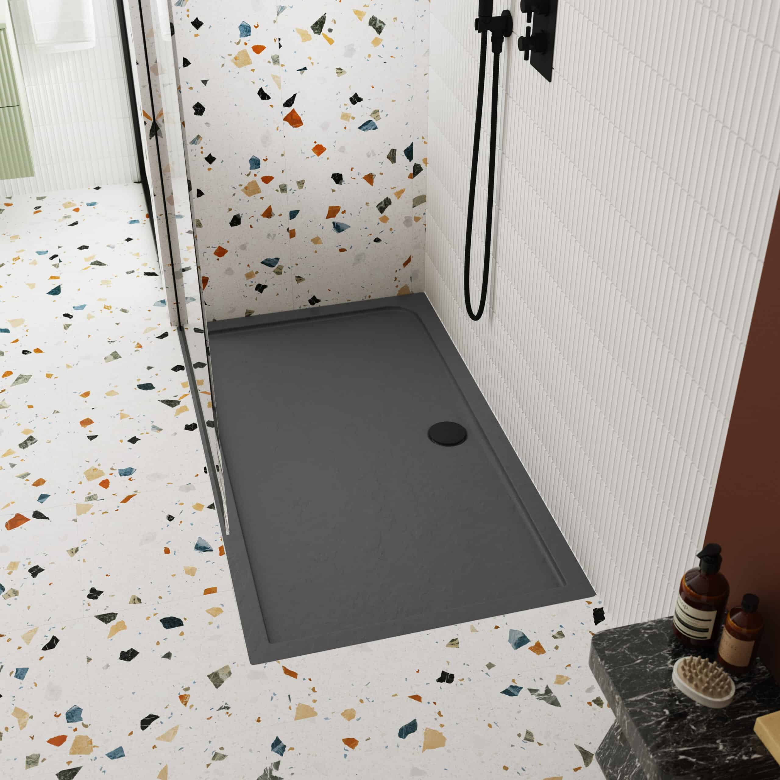 Modern grey shower tray with corner installation, terracotta terrazzo bathroom flooring, contemporary black shower fixtures, and stylish white wall tiles, creating a chic and functional bathroom space.