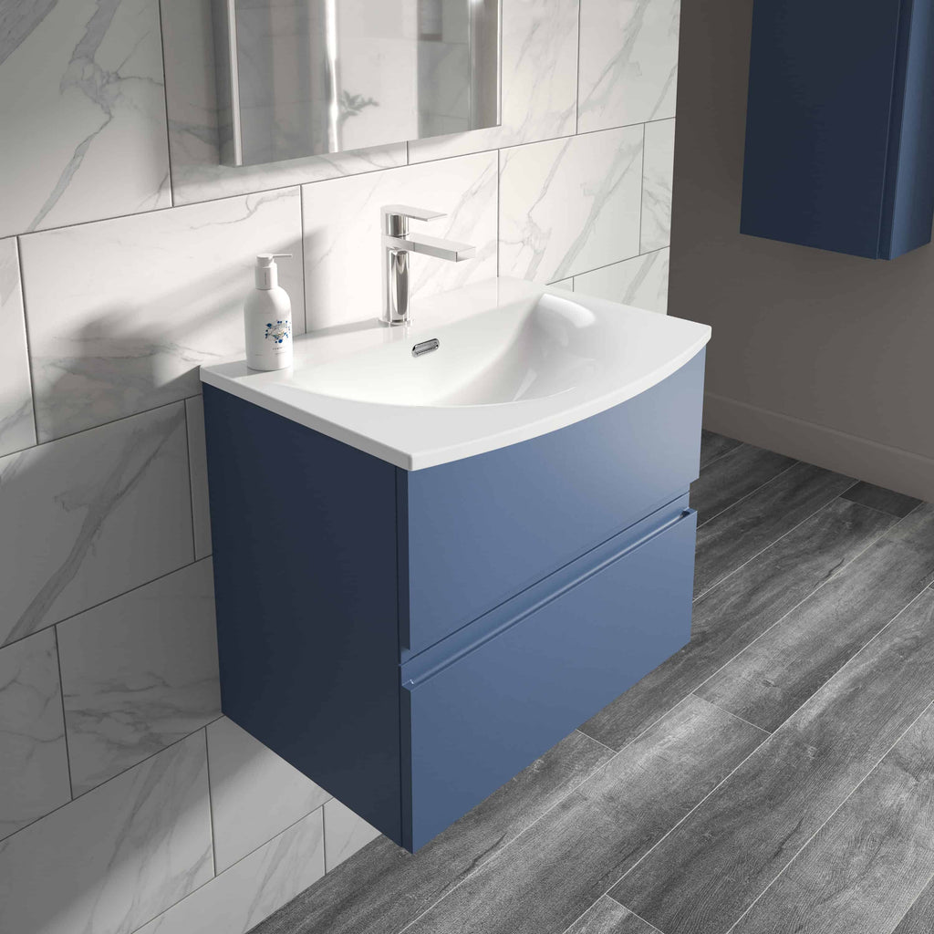 Modern blue bathroom vanity unit with integrated sink and chrome faucet in contemporary bathroom setting, featuring marble tiled wall and grey wood-effect flooring.