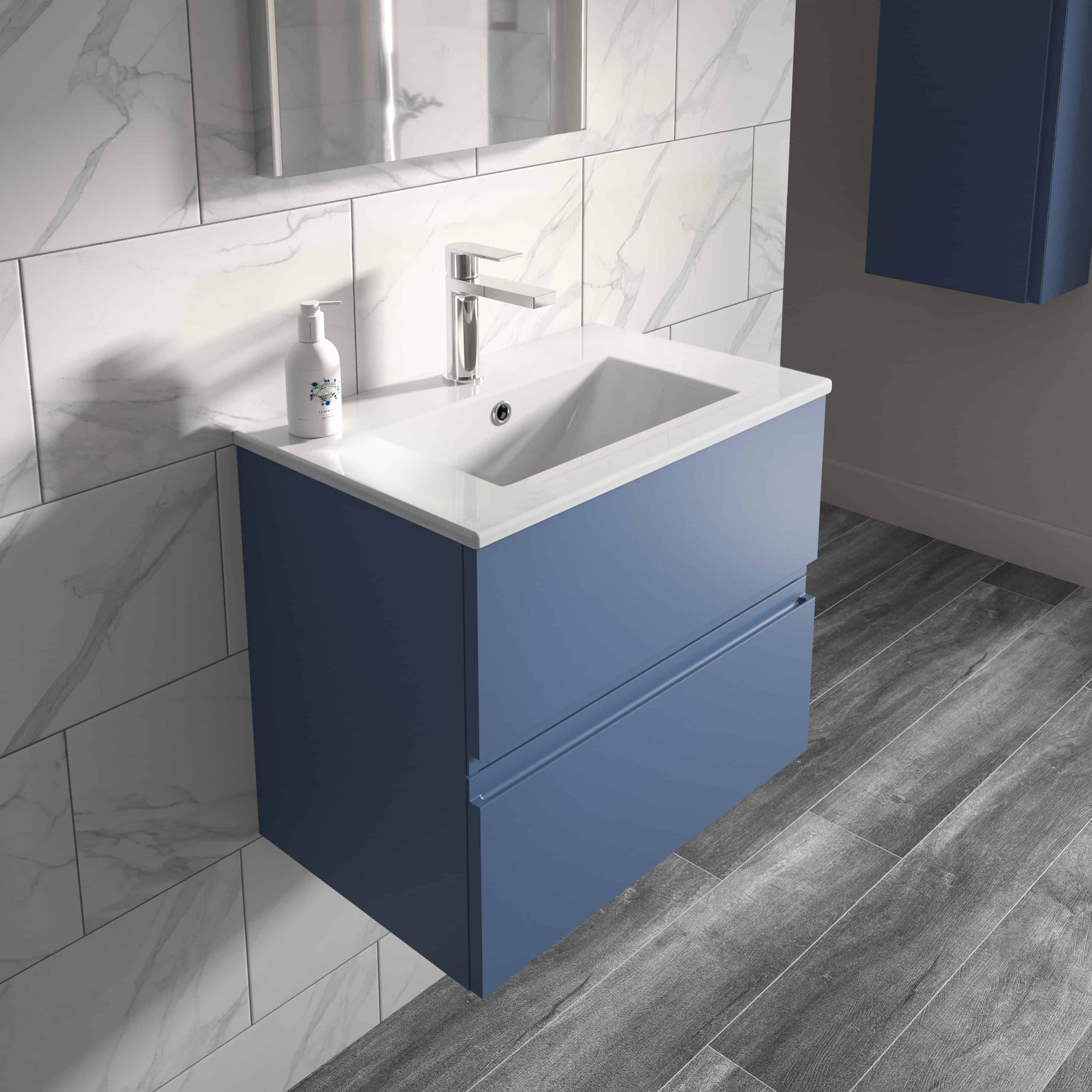Sleek blue wall-mounted bathroom vanity with integrated sink and modern chrome tap, set against marble-effect tiled wall in contemporary bathroom design.
