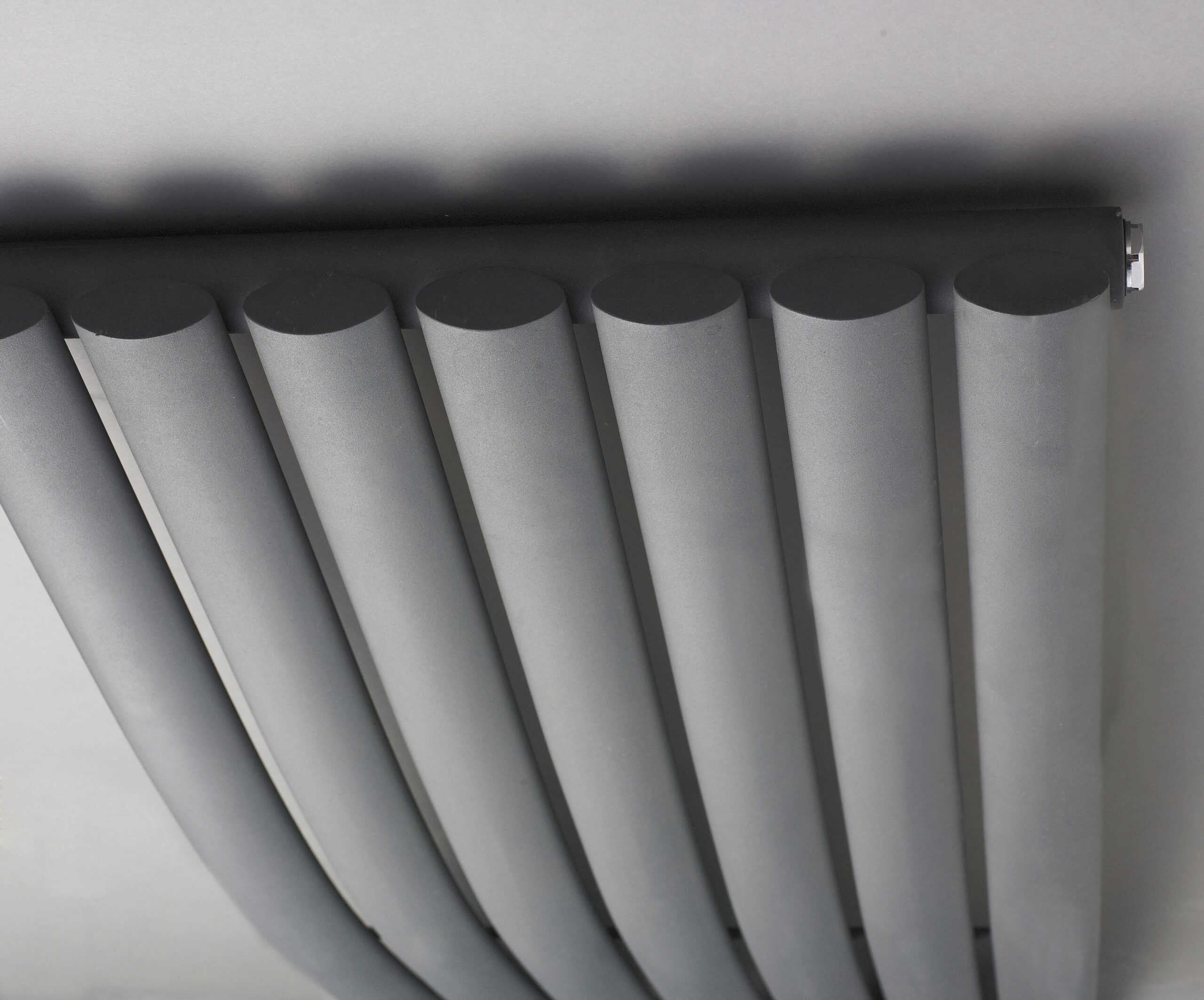 Modern central heating radiator with vertical panels in a contemporary bathroom setting.