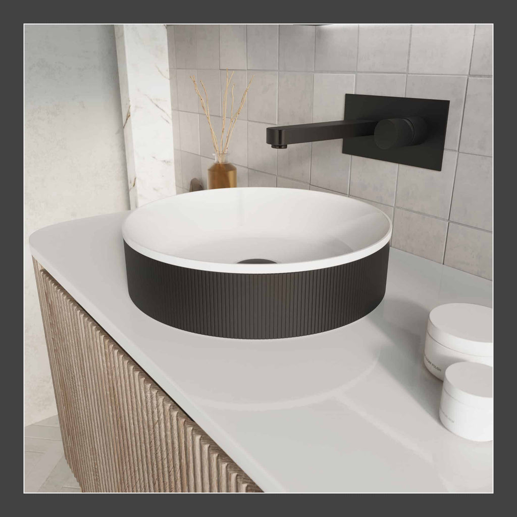 Sleek black and white modern bathroom basin with wall-mounted matte black tap, wooden textured vanity, minimalist accessories, and neutral tile background for contemporary bathroom style.