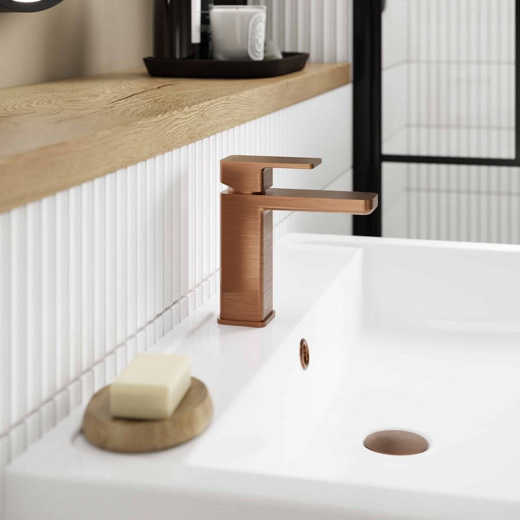 Brushed bronze bathroom sink tap with modern minimalist design, installed on a white ceramic basin in a contemporary bathroom setting.