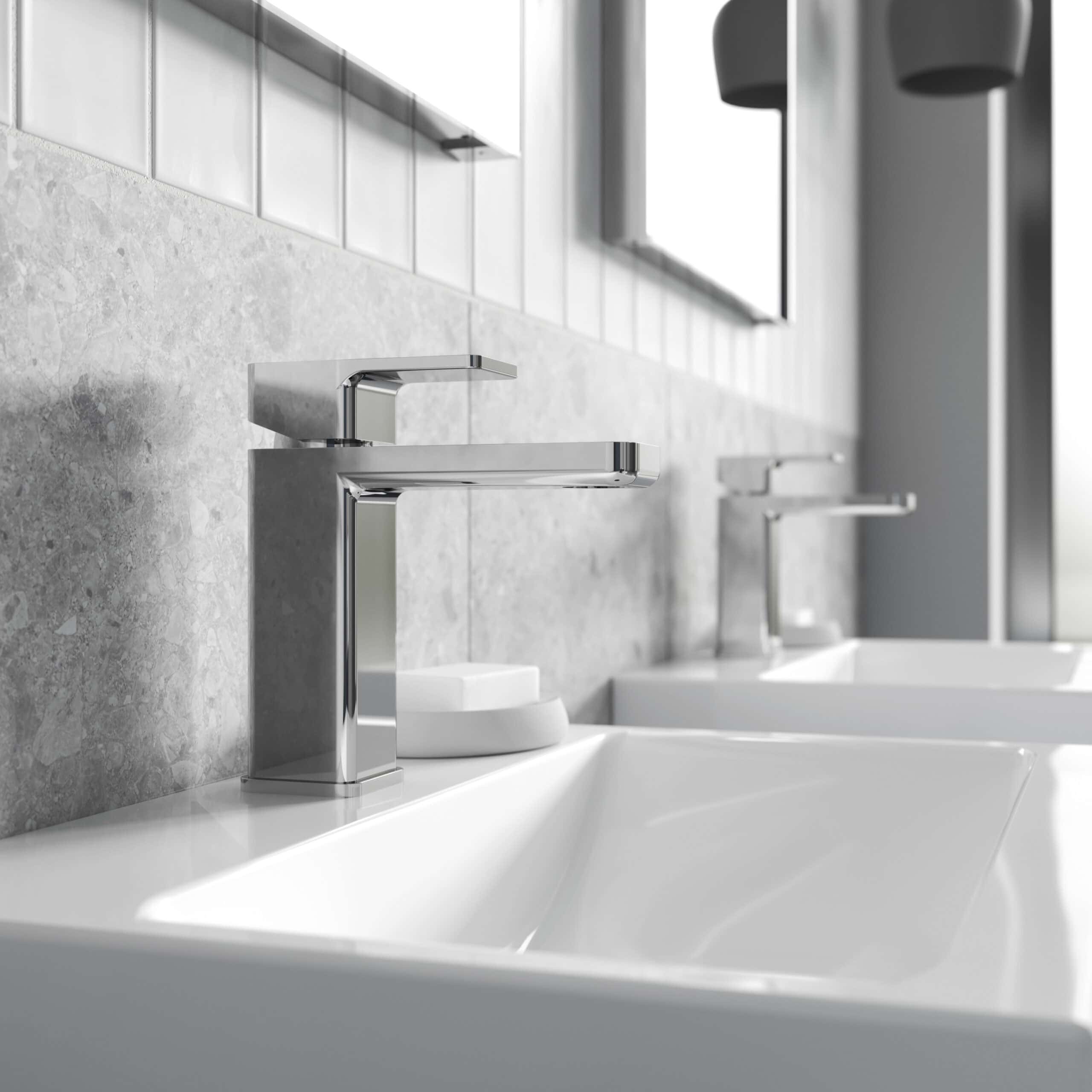 Sleek modern chrome bathroom basin tap installed on white ceramic sink with a textured grey wall background. Perfect for contemporary bathroom designs emphasizing quality fixtures.