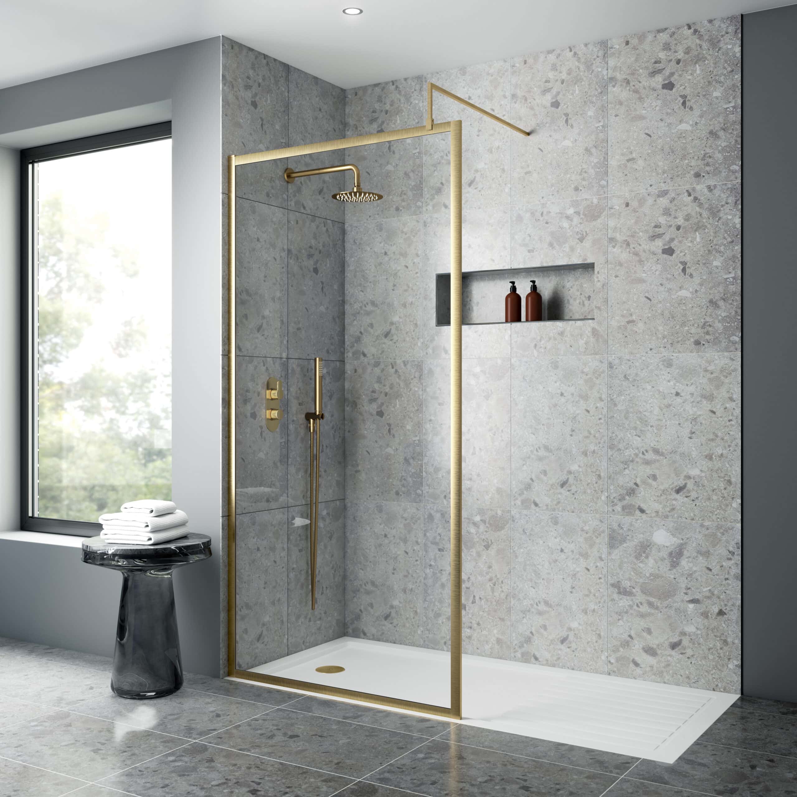 Contemporary walk-in shower with gold fixtures, grey stone tiles, and a built-in niche for toiletries in a modern bathroom setting.