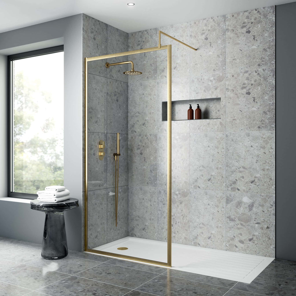 Contemporary walk-in shower with gold fixtures, grey stone tiles, and a built-in niche for toiletries in a modern bathroom setting.