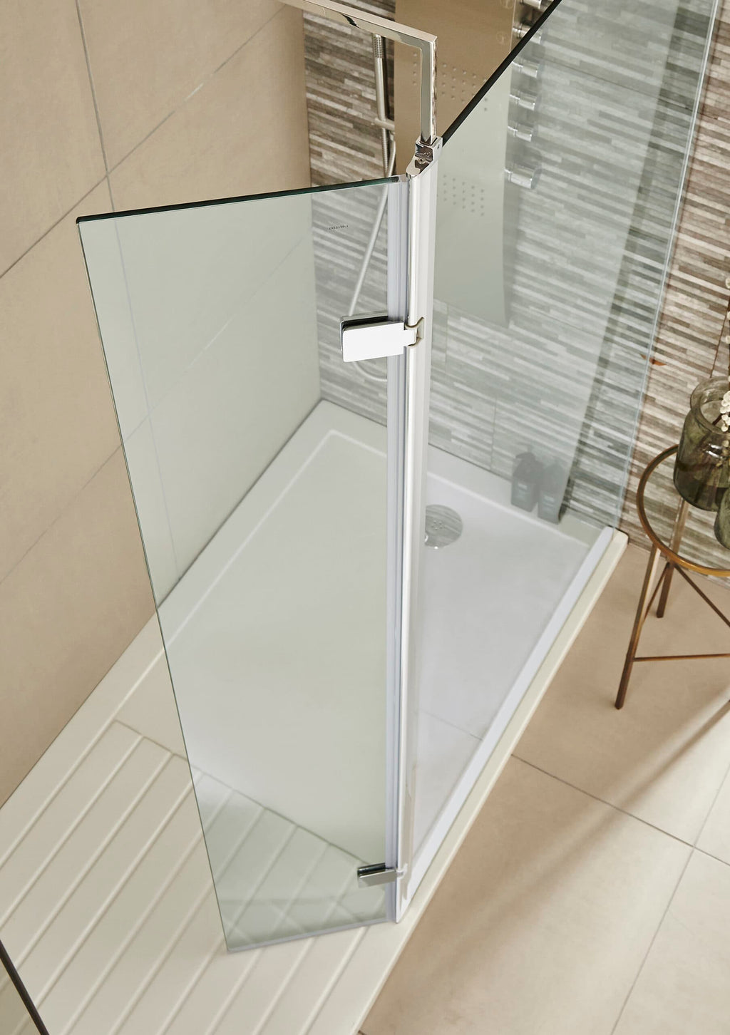 Shower enclosure with clear glass door and chrome trim, installed in a modern bathroom with beige and grey tiles, designed for stylish and functional bathroom renovations.