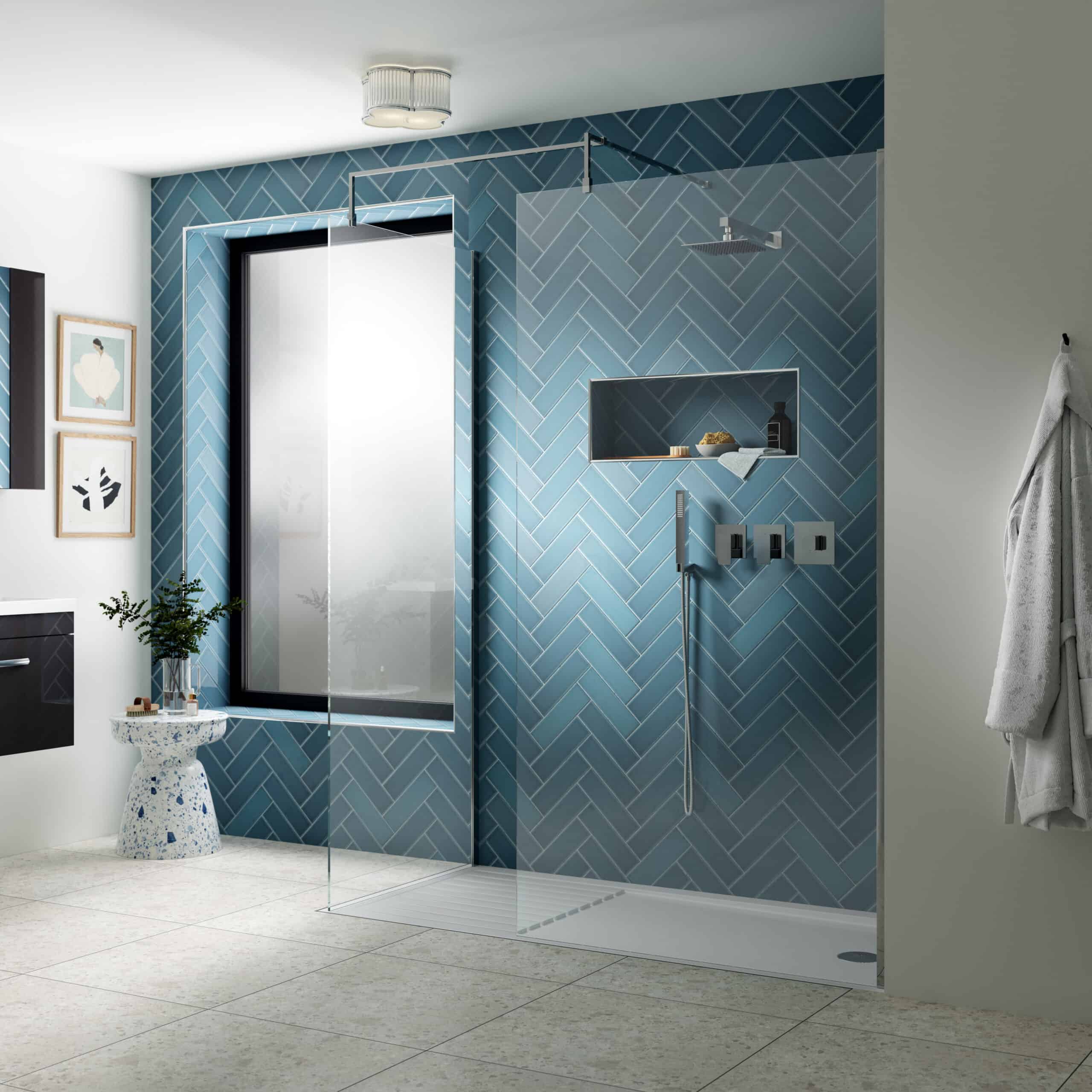 Modern walk-in shower with blue herringbone tiled wall and glass screen, featuring minimalist fixtures and recessed shelf for toiletries, creating a sleek bathroom design.