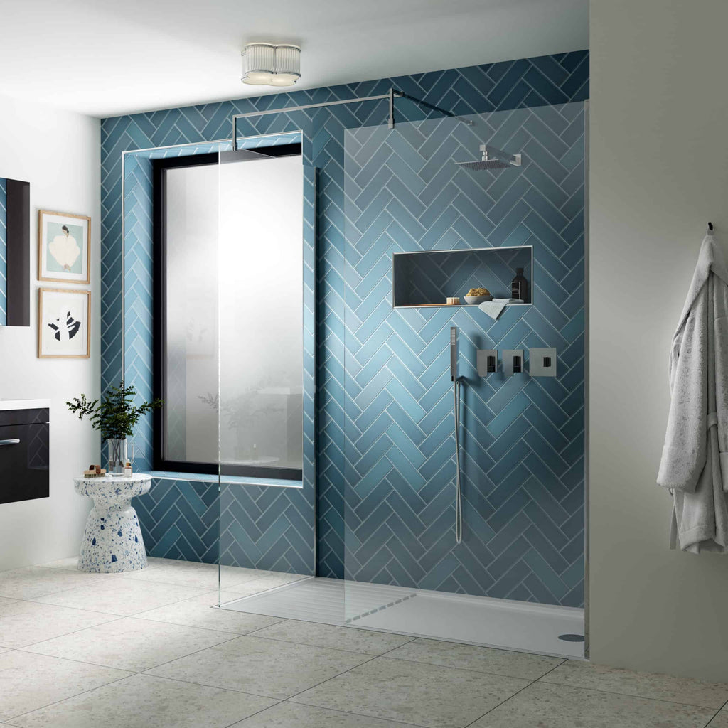 Modern walk-in shower with blue herringbone tiled wall and glass screen, featuring minimalist fixtures and recessed shelf for toiletries, creating a sleek bathroom design.