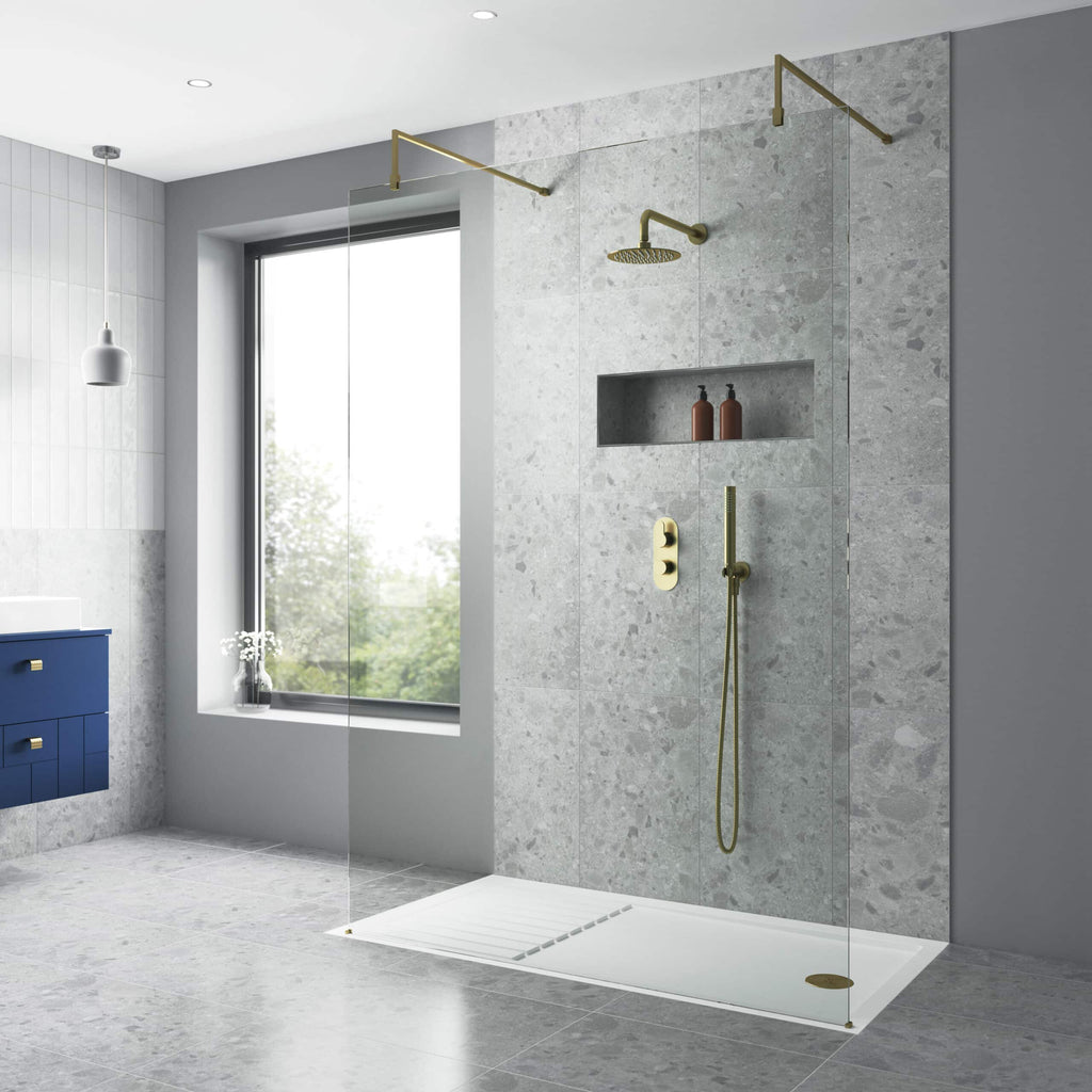 Elegant walk-in shower with clear glass panel, modern brass fixtures, and a sleek grey stone wall design, creating a stylish and functional bathroom space.