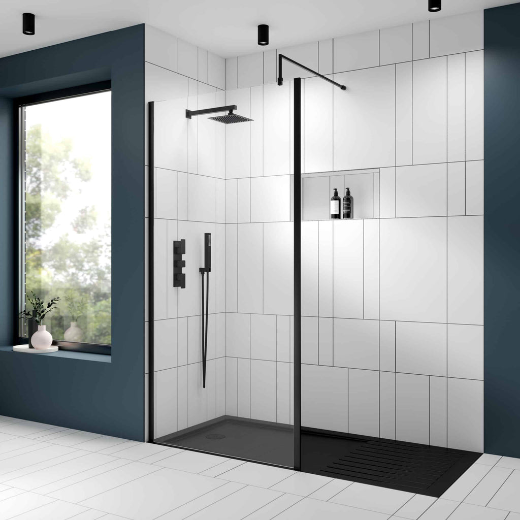 Modern walk-in shower with black fixtures and large white tiles, featuring a built-in niche for toiletries and a sleek black shower tray for contemporary bathroom design.